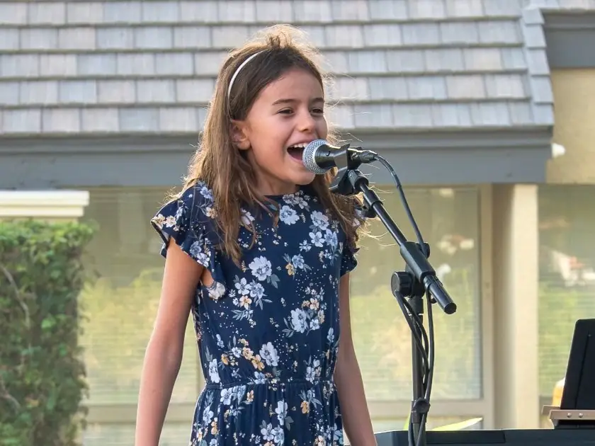 A young student sings proudly at an outdoor OC Music Services recital