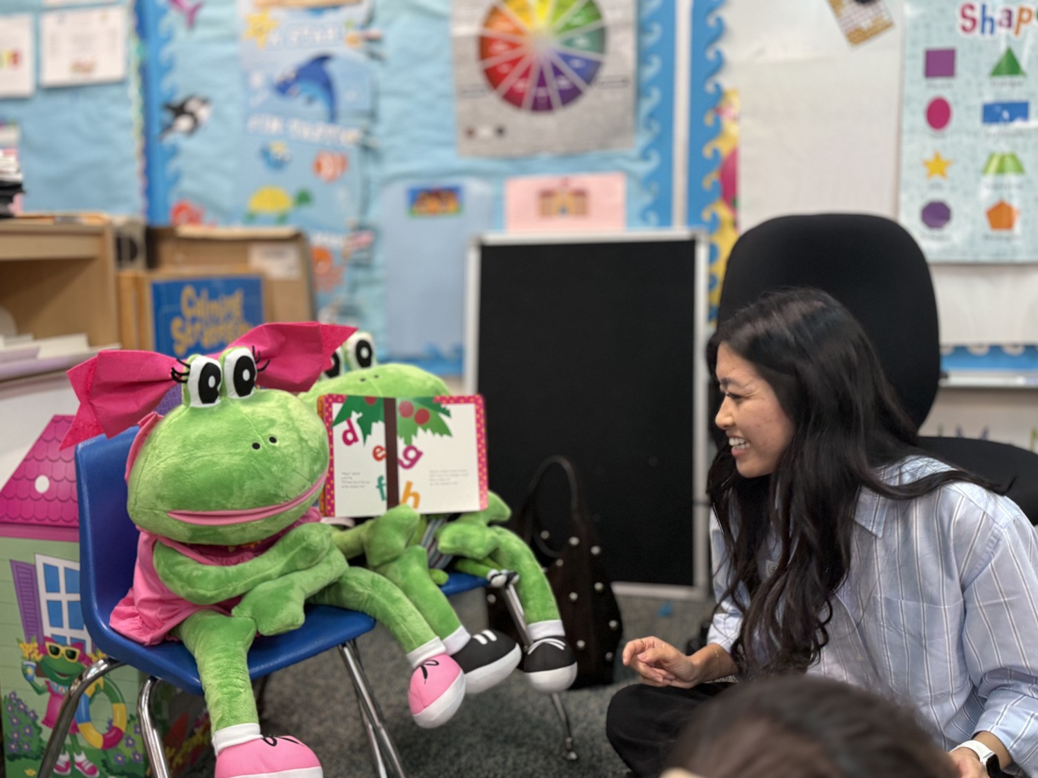 A teacher sharing an alphabet book with frog puppets in a Garden Grove preschool