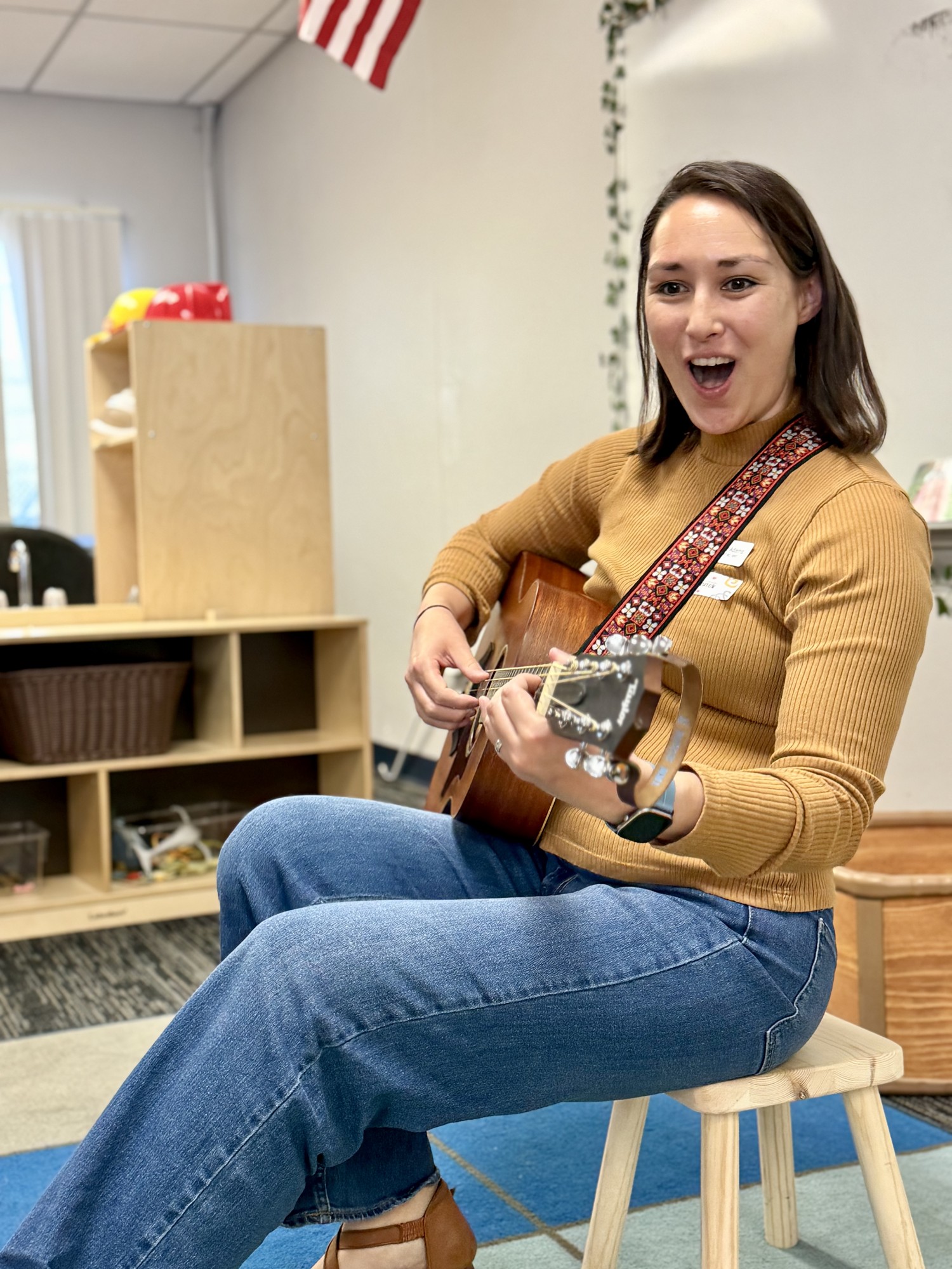 An OC Music Services teacher singing and playing guitar in a preschool classroom